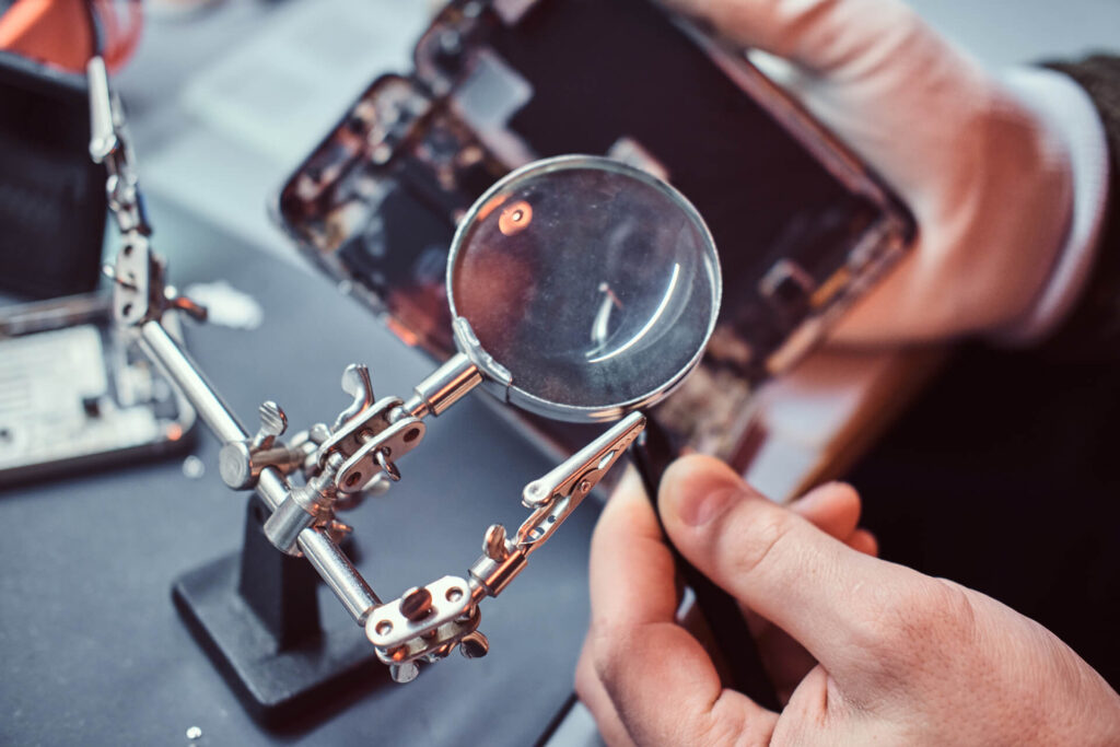 techncian-fixing-iphone-device-under-magnifying-glass